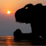 Woman kneeling in silence at the sunset — God, are you still listening?